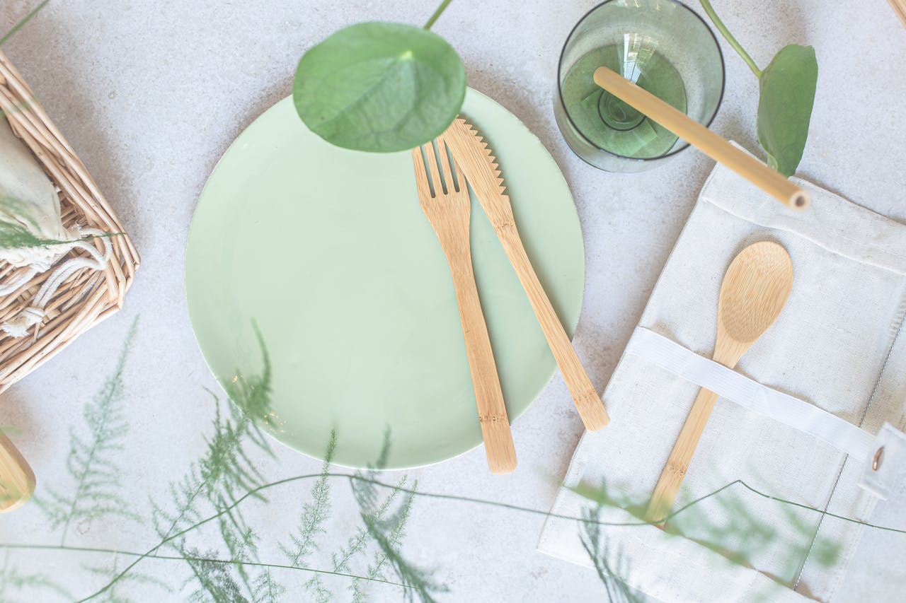 Top view of a green ceramic plate with bamboo utensils and eco-friendly dining accessories.